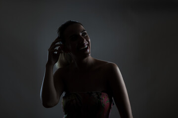 Elegant woman in floral dress smiling joyfully in a dimly lit room