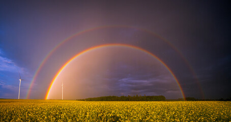 Double rainbow over wind turbines in rural setting focusing on nature and renewable energy