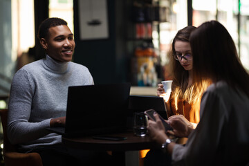 Three multiracial business colleagues having a meeting after work or during coffee break in a restaurant. Friends working at a cafe bar..