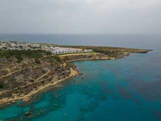 Fototapeta premium Aerial view of hiking trail towards Turtle beach and Anthea's Cave Protaras headland from Konnos Beach. Turquoise Mediterranean sea on a cloudy day.