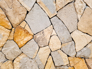 Background of a beige and gray Fieldstone mosaic wall. Old stone wall texture. Abstract stone pattern, home decoration.