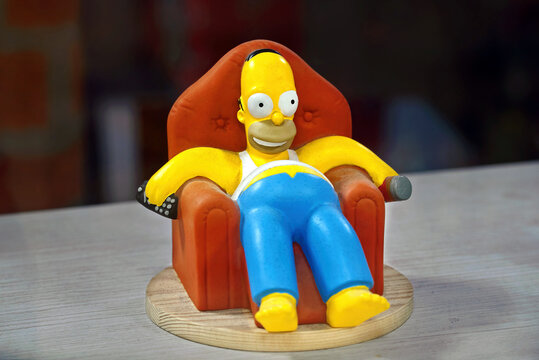 Minsk, Belarus. Jan 29, 2023. Homer Simpson figure holding TV remote and soda can while sitting in chair, collectible figure for enthusiasts of the beloved animated cartoon series