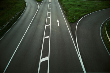 Auf- und Abfädelstreifen einer Schnellstraße zwischen grünem Gras.
