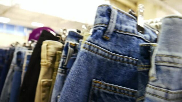 Close-up of many various jeans hanging in a row