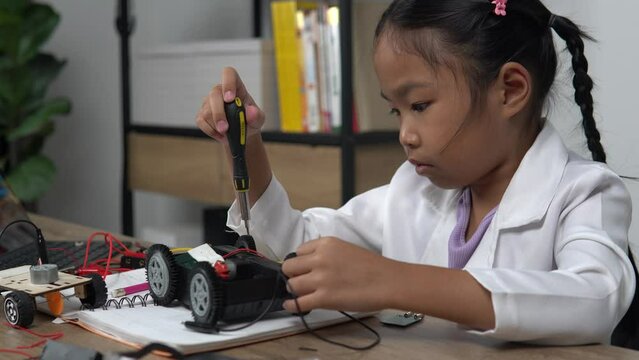Asian girl assembling model car and programming remote control,engaging in STEM activities,developing engineering skills,learning robotics,exploring technology,enhancing creativity through hands-on pr