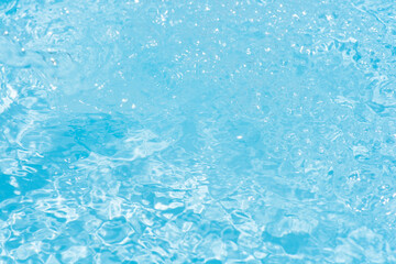 Blue water with ripples on the surface. Defocus blurred transparent blue colored clear calm water surface texture with splashes and bubbles. Water waves with shining pattern texture background.