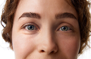 Close-up of female face, brows, eyes and nose isolated on white background. Eyes lenses, brows and...