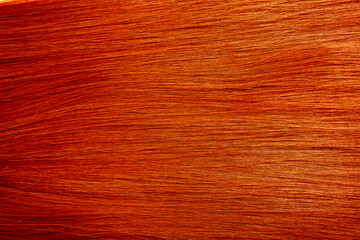 Red hair close-up as a background. Women's long orange hair. Beautifully styled wavy shiny curls....
