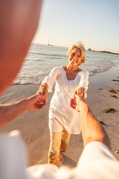 Happy Senior Old Retired Couple Walking Holding Hands on Beach at Sunset