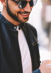 Cropped image of cheerful handsome guy reading information from browsed on smartphone website,cheerful man satisfied with internet connection downloading multimedia on cellphone from network outdoors