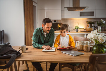 Son read a book and have fun while spend time with his father at home