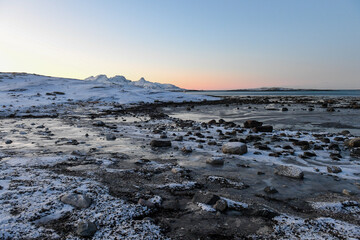 Wide angle shot of ice and boulders along the Norwegian coast, on a snowy winter morning.