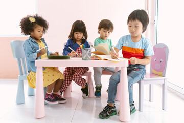 Group of Multi-ethnic children drawing with colored pencil in art classroom at kindergarten. Group...