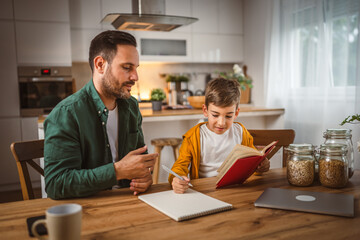 Son read a book and have fun while spend time with his father at home