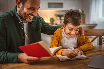 Father with book assistance and help son to do homework together home