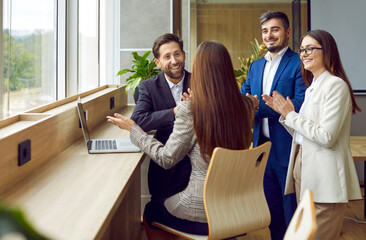 Group of a happy business people standing in office near the workplace and making successful deal...