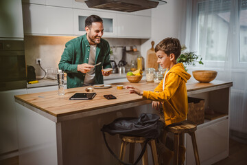 Dad prepare chocolate cream on bread while son pack backpack school