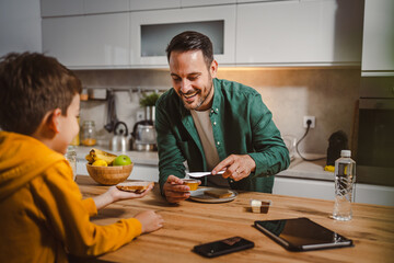 Dad prepare chocolate cream on bread while son pack backpack school