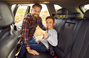 Father and child boy don't forget about car safety belt. Happy dad and his son who just buckled up...