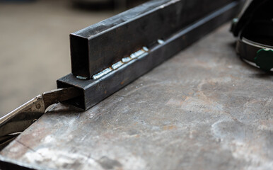 Conceptual image at work: in a workshop selective focus on the welding point of two metal bars. Work concept, metal craft work, repair, creativity.