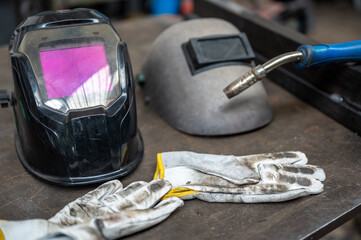 A conceptual image about safety at work: a modern welding helmet and a vintage one next to it. On...