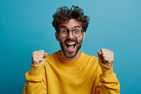 Young Man in Yellow Sweatshirt Celebrates Victory with Excited Expression