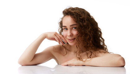 Obraz premium Portrait of tender young woman with no makeup perfect face, curly brown hair posing isolated on white background. Concept of natural beauty, skincare, wellness, cosmetology, cosmetics