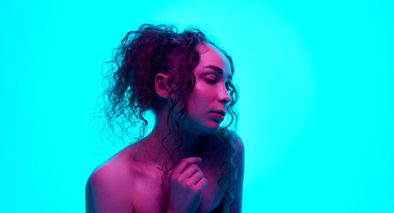 Portrait of beautiful young woman with curly hair in pony tail, well-kept skin, with bare shoulders...
