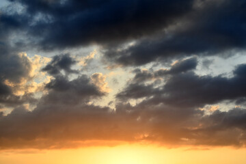 Dramatic dark fluffy clouds with sunset sky. Beautiful summer nature in the evening. Cloudscape background. 