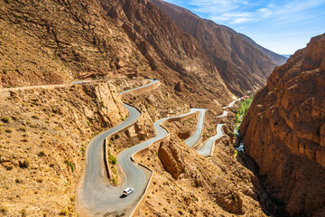 Car driving on zig zag road bends in desert mountain landscape of Dades Gorge canyon, Morocco, North Africa