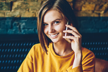 Half length portrait of cheerful female manager talking with client on digital telephone working...