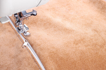Modern sewing machine special presser foot with beige corduroy fabric and thread, closeup. Sewing...