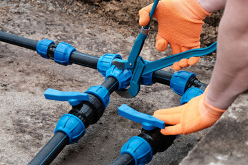 Plumber using a wrench tightens a compression fitting onto a HDPE pipe with a tap, installing a...