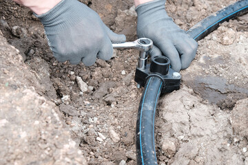 plumber installs a saddle fitting for connecting a sprinkler, automatic watering of the lawn...