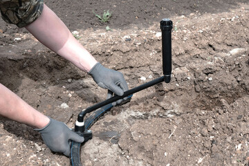 Plumber installs a sprinkler for automatic watering using a flexible connection, hands close-up