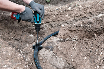 plumber installs a saddle fitting for connecting a sprinkler, automatic watering of the lawn...