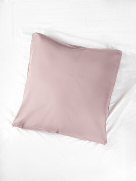 Square pillow in a light pink pillowcase. Vertical