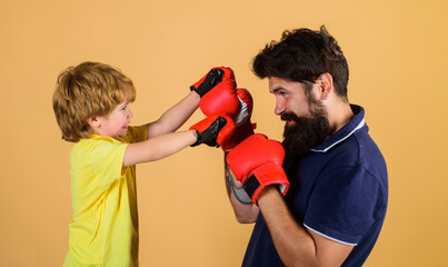 Kid boxer with coach at boxing training. Small son doing boxing exercise with father in gym. Child...