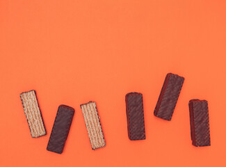 Chocolate wafers lined up on an orange background. Copy space