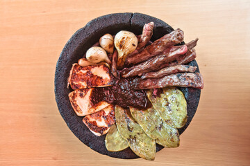 Mexican food, Aztec molcajete with flank steak and drunken sauce, nopales and fresh cheese with molcajete sauce