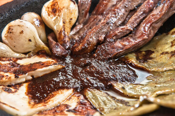 Mexican food, Aztec molcajete with flank steak and drunken sauce, nopales and fresh cheese with molcajete sauce