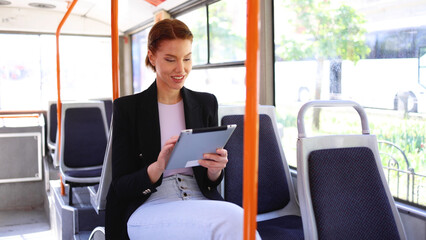 Beautiful, young businesswoman riding in a city bus and using a digital tablet