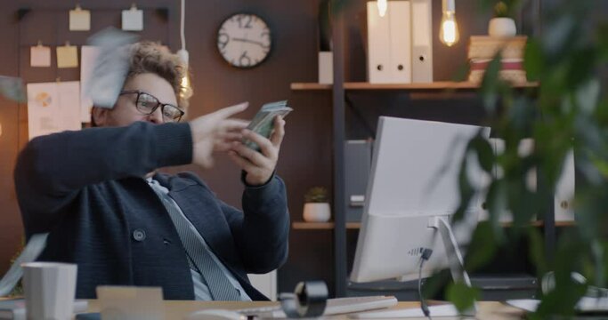 Loop of overjoyed businessman throwing cash money having fun enjoying financial success in office in evening. Business and rich people concept.
