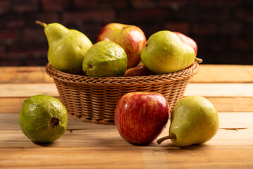 Basket with fruits on rustic wooden surface and dark background, selective focus.