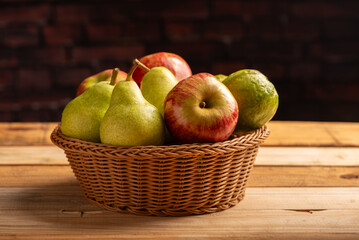 Basket with fruits on rustic wooden surface and dark background, selective focus.