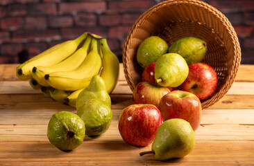 Basket with fruits on rustic wooden surface and dark background, selective focus.
