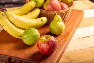 Basket with fruits on rustic wooden surface and dark background, selective focus.