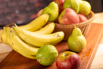 Basket with fruits on rustic wooden surface and dark background, selective focus.