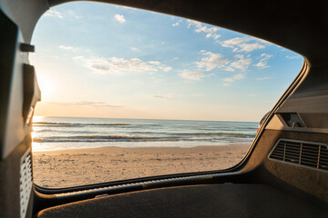 Car trunk open against a background of sunset over the beach