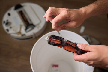 Removing pet fur from a brush and placing it in a bowl as part of grooming routine